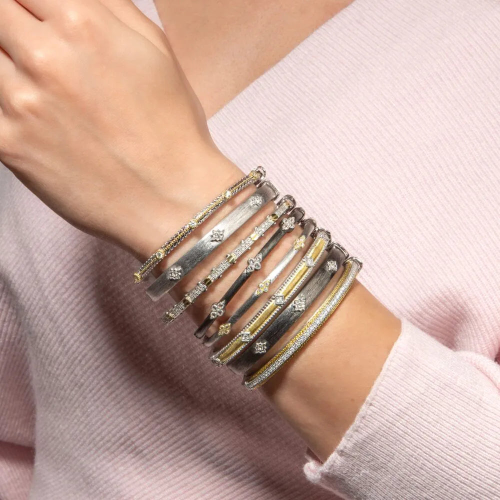 multiple bangles on model wrist of different types of metals